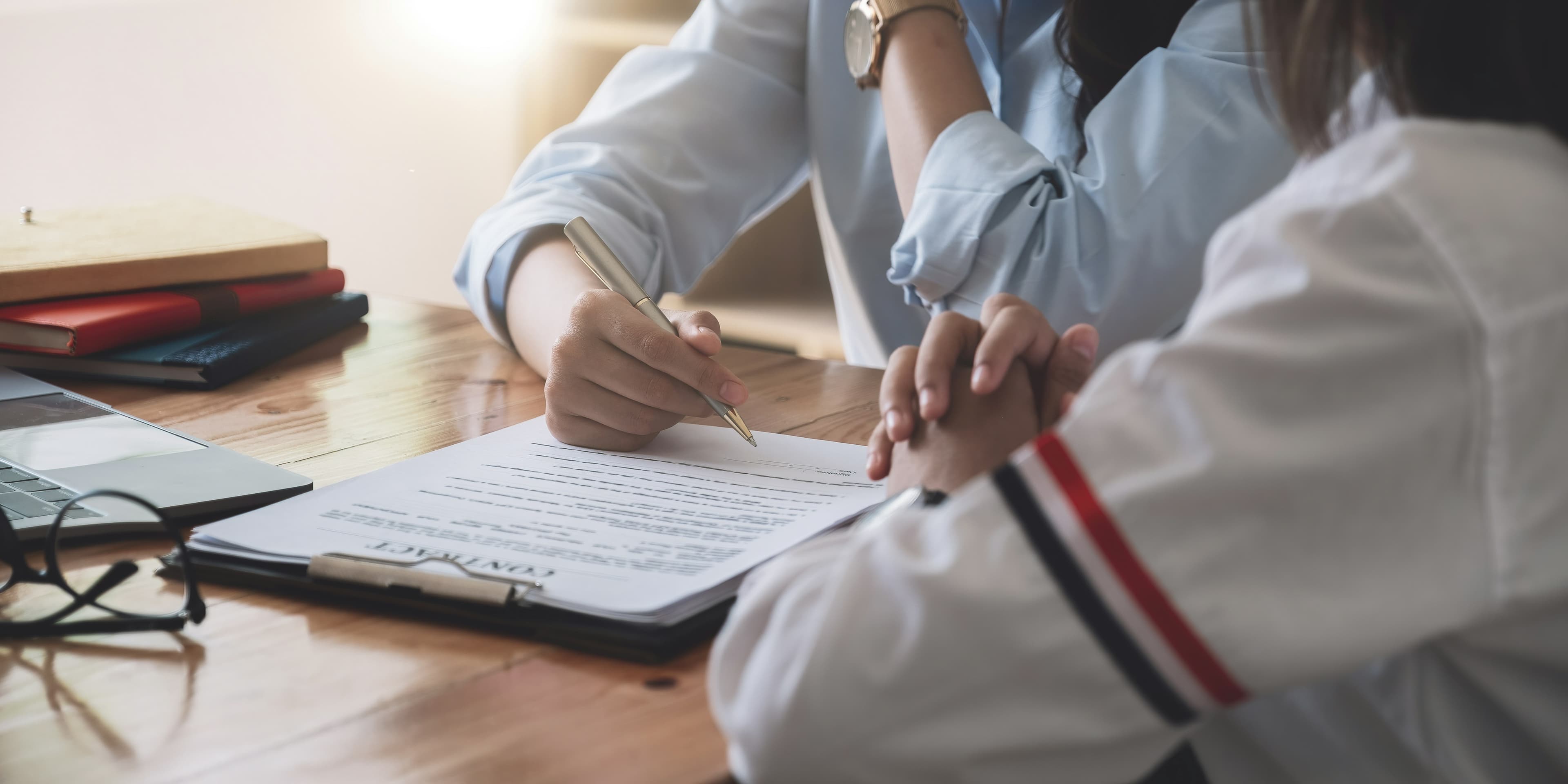 Close-up of hands signing paperwork